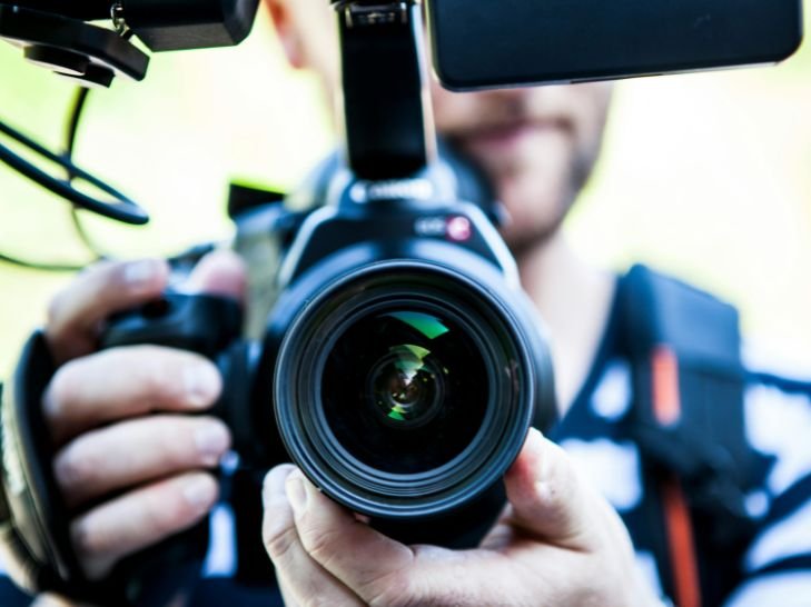 Photographe en train de filmer avec une caméra professionnelle, gros plan sur l’objectif.